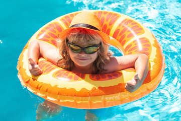 Kid boy in sunglasses in pool in summer day. Children playing in swimming pool. Summer holidays and vacation concept.