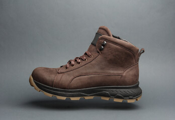 Brown leather boot floating on dark gray background
