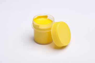 Jar of yellow gouache paint on a white background