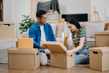 Young couple with big boxes moving into a new house, new apartment for couple, young asian man and...