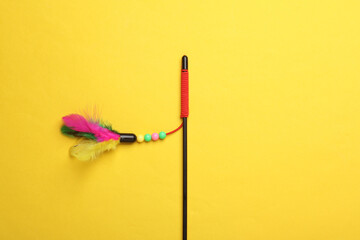 Stick with feathers on yellow background. Cat toy
