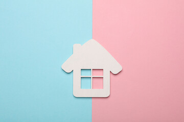 White wooden figurine of a house on a blue-pink background
