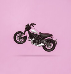 Toy motorcycle levitating on pink background with shadow