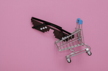 Pixelated 8 bit sunglasses in shopping cart on pink background