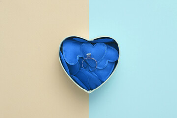 Golden ring in Box with hearts on pink blue background. Love concept, valentine's day, february 14th celebration, marriage proposal