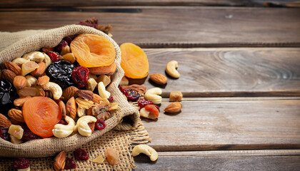 Nuts and dried fruits mix on a rustic sack and wooden background. Healthy food.