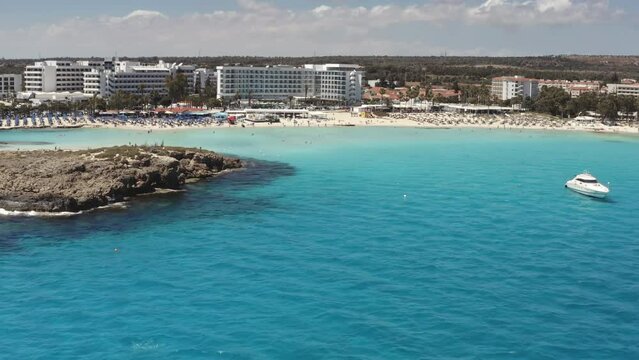 Nissi Beach in Cyprus. Stony seaside coast with blue turquoise sea water in Ayia Napa. Beautiful coastal nature landscape. Travel destination for tourists on summer holiday vacation. Aerial view zoom