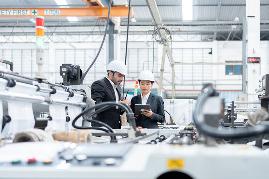 senior official Industrial plants are European and Asian male and female engineers. Wear a suit and helmet. View business work with laptop, exporting plastics and energy to the world market.