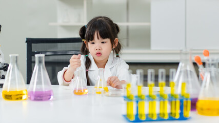 Asian little cute girl students in lab coat making test tube science experiments chemical laboratory in study room at school. Education research and development concept learning kids.