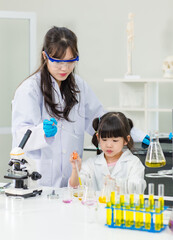 Asian woman teacher and little children girl making science experiments tests in chemical laboratory study room. Education research and development concept learning for kids.