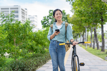 Happy Asian woman in casual clothes using a smartphone and a bicycle