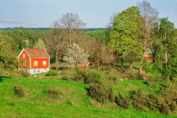 Red cottage in a rolling landscape in spring