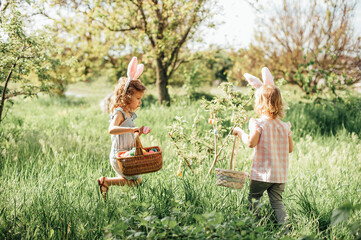 Easter egg hunt. Group Of Children Wearing Bunny Ears Running To Pick Up colorful Egg On Easter Egg Hunt In Garden. Easter tradition - 737802535