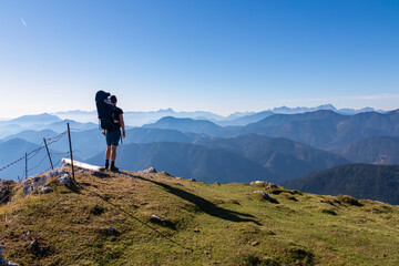 Man with baby carrier looking at magical mountain peaks of Karawanks and Julian Alps seen from Goldeck, Latschur group, Gailtal Alps, Carintha, Austria. Mystical atmosphere in Austrian Alps in summer