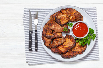 fried juicy pork steaks with ketchup on plate