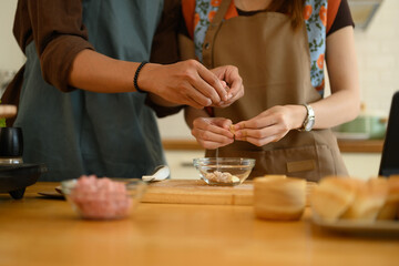 Young couple hands peeling garlic on chopping board for cooking in the kitchen