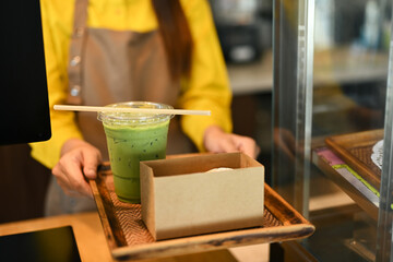 Waitress serving cold drink with paper straw and cake in a cardboard takeaway box to customer