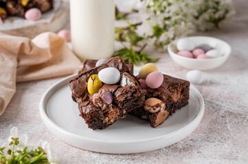 Chocolate brownie with Easter candies in the form of colored eggs with a bottle of milk. Easter...