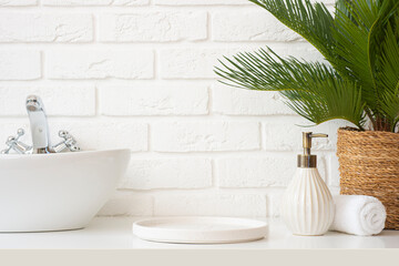 Round podium for bathing or cosmetics products near bathroom sink, dispenser, plant and spa towel