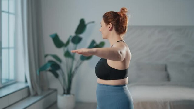 Woman training exercising at home. Middle aged female fitness newcomer doing body rotations exercises to keep herself in shape, to lose weight. Sport lifestyle, workout newcomer, wellness concept.