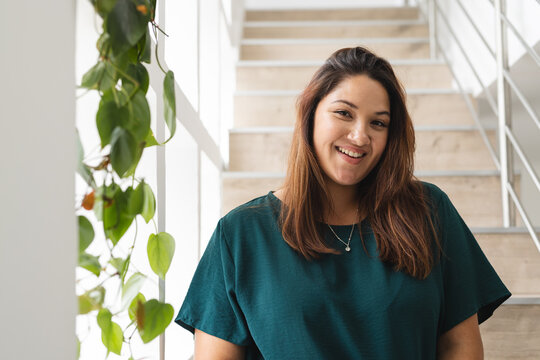 Young biracial plus size woman smiles warmly indoors, with copy space unaltered