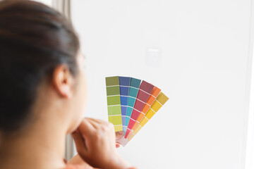 Young biracial woman examines color swatches at home