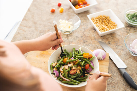 Young plus size biracial woman enjoys a healthy meal at home unaltered - Powered by Adobe