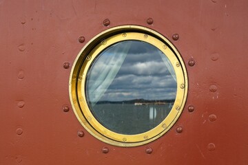 Closeup of round small porthole window on the side of vessel.