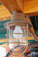 Closeup of an old ship bulkhead lantern made of metal with light bulb.