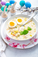Homemade polish Easter soup with addition of sausage, hard boiled egg and vegetables in a bowl