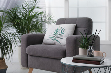 Soft pillow with printed tropical leaf on armchair indoors