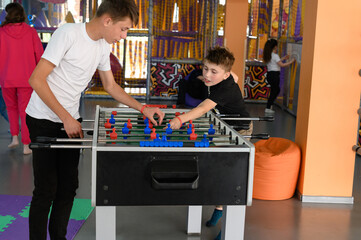 Two boys are playing table football in the playroom