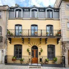An elegant townhouse in a bustling urban neighborhood, with wrought iron balconies, decorative window shutters, and vibrant flower boxes adding character to the facade.