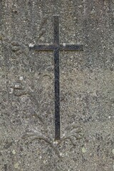 Closeup of gravestone engraving of a cross.