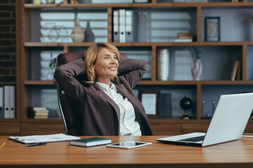 Experienced senior businesswoman taking a break, leaning back in her chair with satisfaction in a modern home office setting.