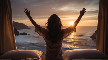 a woman with her arms raised looking at the sunset