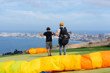 Man learning to use the controls of a paraglider with an instructor