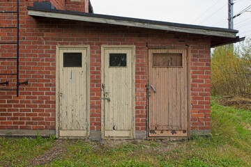 Three wood doors on a red brick building.