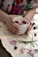 Female hands holding a cup of cappuccino with flowers on a book background