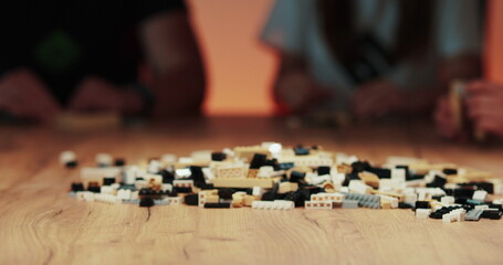 Adult hands take plastic Lego toy blocks and construction game blocks. The concept of teamwork-play, coordinated work.