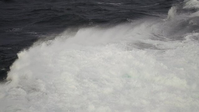 Stormy waves in the open sea. Strong wind raises water spray into the air.