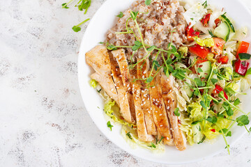 Lunch oatmeal porridge with grilled chicken fillet and fresh vegetables. Healthy balanced food. Trendy food. Top view, flat lay