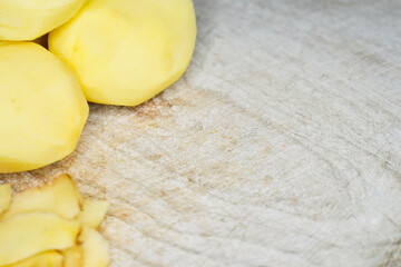 Raw potatoes peeled on wooden table top.