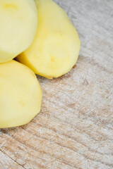 Raw potatoes peeled on wooden table top.