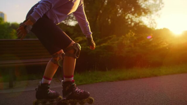 Unrecognizable young woman rollerblading in the park during sunset