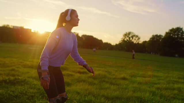 Young woman rollerblading in the park during sunset