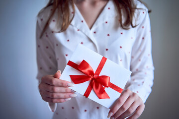 gift certificate in the hands of a teenage girl wearing white pajamas with red hearts