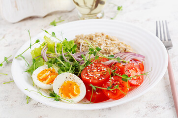 Breakfast oatmeal porridge with boiled eggs and fresh vegetables. Healthy balanced food. Trendy food.