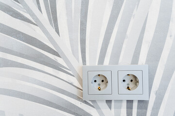 A closeup shot of two electrical outlets on a zebraprint wallpapered wall
