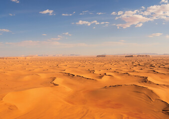 Fototapeta na wymiar Grand désert avec sol et terre sèche et infertile à cause de la sècheresse et du réchauffement climatique. Dunes de sable avec un ciel bleu en fond.